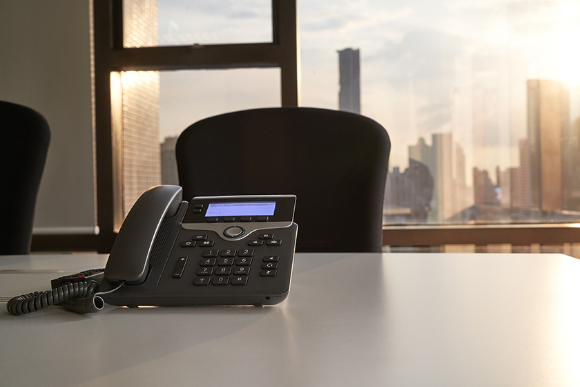A VoiP phone in a meeting room at sunrise.